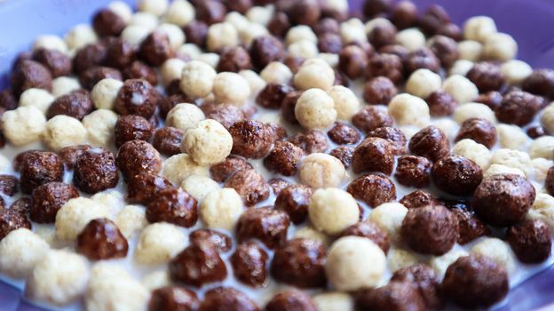 Healthy breakfast with milk on the table in a deep plate. Whole grain chocolate and milk balls. Healthy cereal breakfast. Children's breakfast. Baby food. Balanced diet. Dry ready and quick snack.