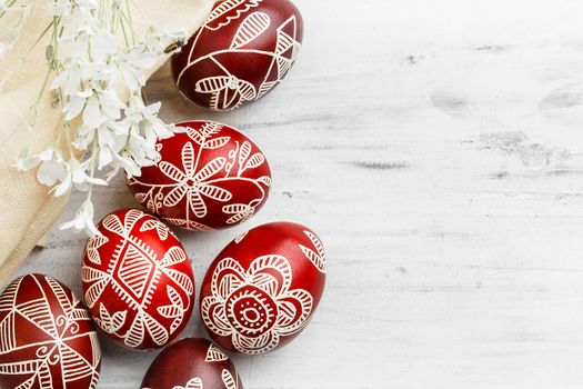 Red and white handmade Easter eggs. Ukrainian pysanka decorated with wax-resist dyeing technique. White wooden background with copy space for text