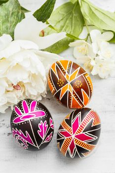 Three handmade Easter eggs decorated with wax-resist dyeing technique. Ukrainian pysanky on the table. Vertical composition