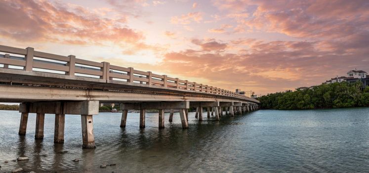Sunset sky over bridge over Hickory Pass leading to the ocean in Bonita Springs, Florida.