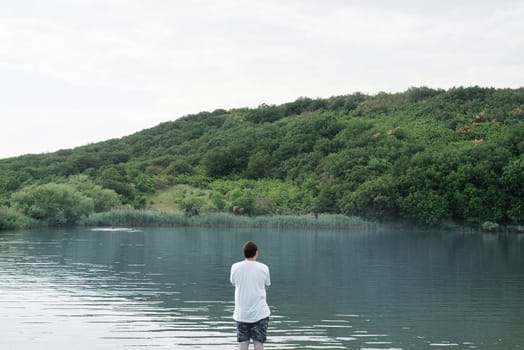 Nature and travel concept. Back view of a man standing near the lake