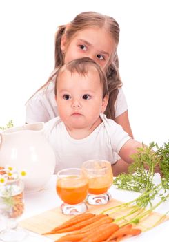 Nice blond baby girl with glass of carrot juice