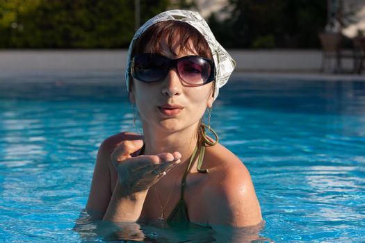 Young lovely woman posing in the pool at mediterranean resort on beautiful sunny summer day