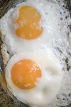 Fried eggs from two eggs are fried in a frying pan. Top view, close-up.