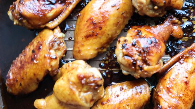Fried chicken wings with a crust in a pan close-up. Baked chicken in teriyaki sauce on a baking sheet in the oven, selective focus