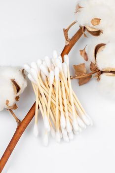 Bamboo cotton swabs with a branch of cotton flower on white background. Zero Waste, sustainable lifestyle concept