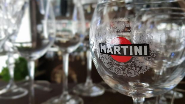 Martini glasses are in the bar. The inscription on the glass and the logo martini sticker. Focus and color concept. A brand of Italian-made vermouths and sparkling wines. Italy, Turin - October 1, 2020