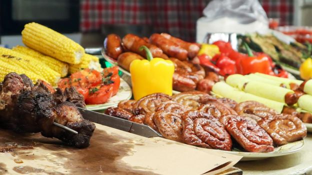 A counter with trays containing grilled sausages and meat. Round barbecue sausage street food showcase. Freshly grilled round sausages at a street food festival. A variety of meat delicacies.