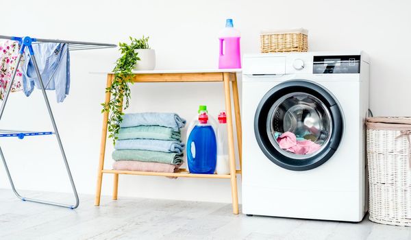 Washing machine with laundry in bathroom and furniture with detergents for cleaning and housework