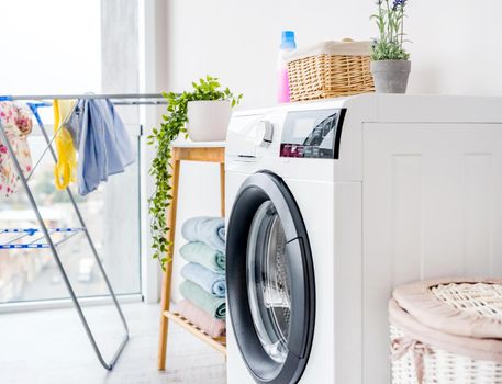 Automatic washing machine in bathroom and furniture with detergents for cleaning and housework at home. Laundry interior
