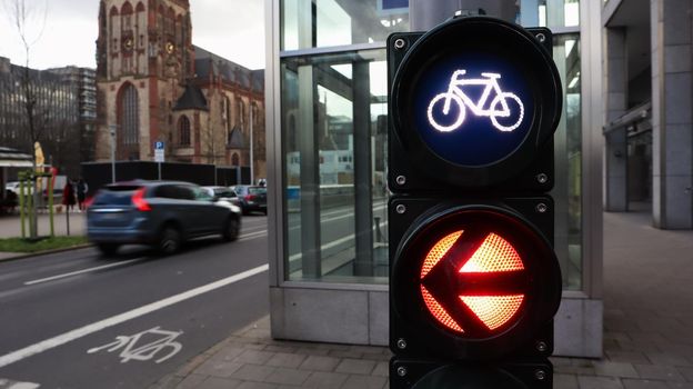 Dusseldorf, Germany - February 28, 2020: traffic light for bicycles close-up with a busy city in the background at a crossroads in Germany. Cyclists wait for a traffic light to cross the street