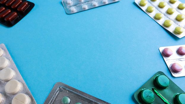 colored medicines and pills in packs on a blue background. Copy space. Pharmacology and medicine are fighting for health. Treatment of various diseases