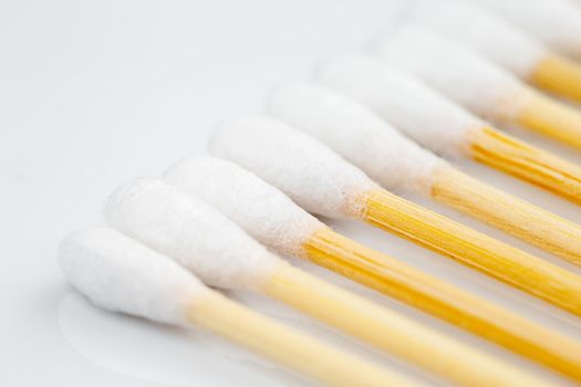 Wooden cotton swabs in a row on white background. Selective focus