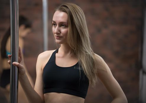 Young pretty woman in sport clothes staying next by the pole. Portrait