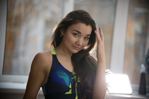 Young pretty woman in sport bra in training studio. Looking in the camera, flirting. Portrait