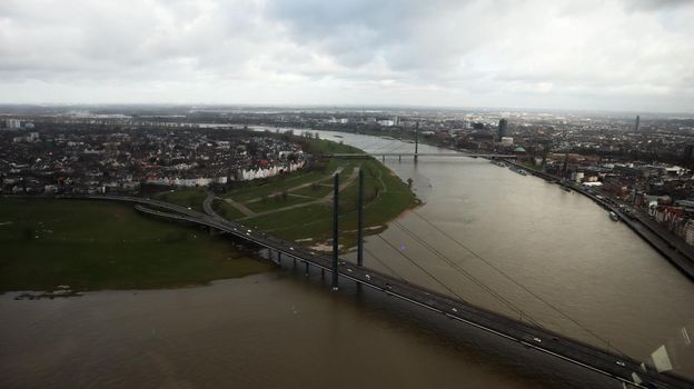 Dusseldorf, Germany - February 19, 2020: view from a high tower on a cityscape. View of the Oberkasseler Brucke bridge, architecture, Rhine river, roads with cars in the morning on a sunny day.