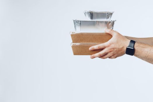 Courier hands giving packed food delivery close up against grey background