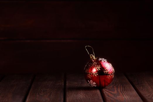 Christmas New Year decoration. Red vintage ball with golden on wooden table dark wooden background side view