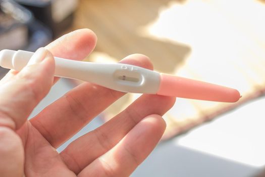 Hand holds pregnancy test over the bright background