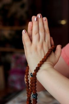 Woman hands holding rudraksha rosary with the namaste mudra