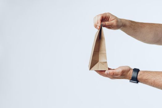 Courier hands giving packed food delivery close up against grey background