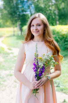 Lovely young girl with the flower bouquet at the nature park