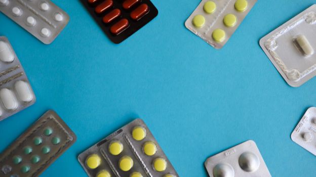 colored medicines and pills in packs on a blue background. Copy space. Pharmacology and medicine are fighting for health. Treatment of various diseases