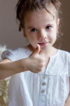 Cute Little kid girl holds thumb up.