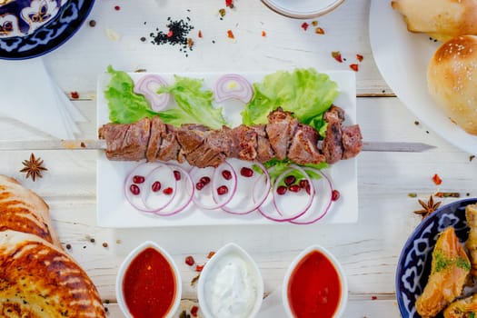 Top view of grilled meat on skewer, over the white plate, with sauces, great image for your needs.