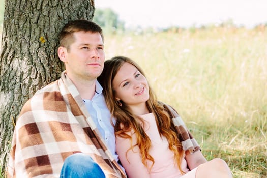 Loving pair relaxing near the tree on the nature