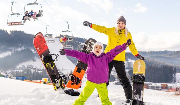 mother and daughter with snowboards at winter resort