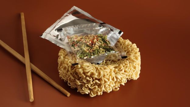 Raw instant noodles with chopsticks and spices. Copy space asian food. pasta, for the preparation of which it is enough to pour boiling water and wait a few minutes. flavored spaghetti