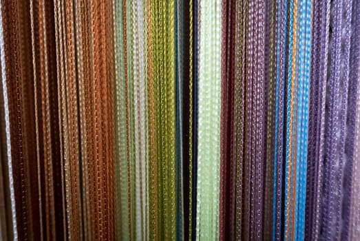 Textile strings and ropes hangs in a fabric shop. Abstract background