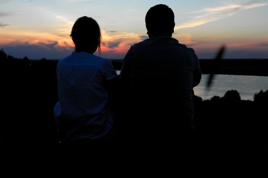 Young couple silhouette against sunset sky. Romantic eveningn.