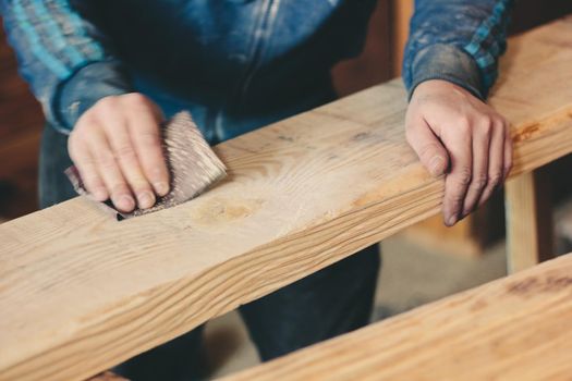 hands with the sandpaper treat the wooden plank. Great photo for your needs.
