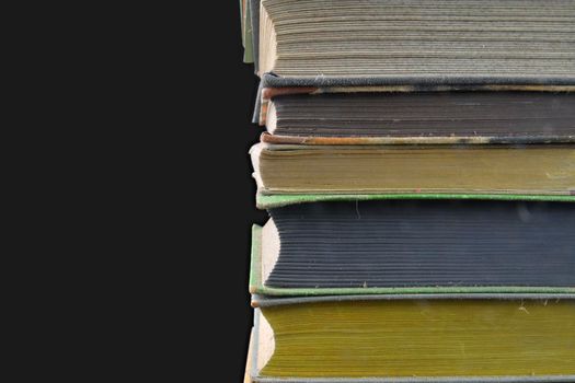 Pile of hardcover vintage books isolated with copy space. Black background. Close-up.