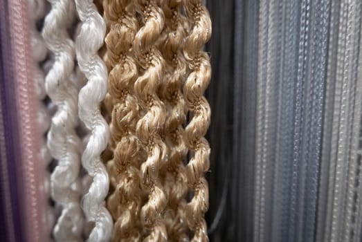Textile strings and ropes hangs in a fabric shop. Abstract background