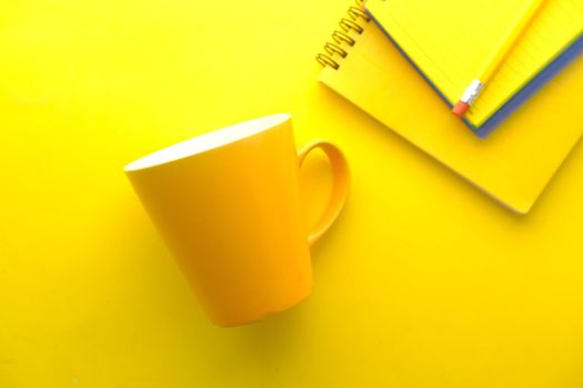 yellow color mug mockup with with notebooks on table