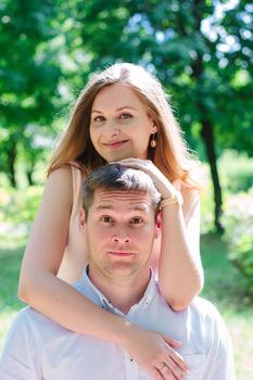 Young couple - girl huggs guy from a back and smiling