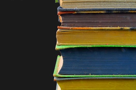 Stack of hardcover vintage books isolated with copy space. Black background.