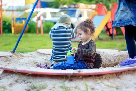 Little kid girl playing with the sand on the playground