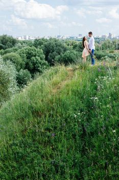 Lovely young couple look to each other against the city, nature and sky