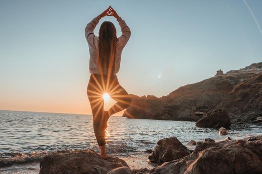 Young woman in swimsuit with long hair practicing stretching outdoors on yoga mat by the sea on a sunny day. Women's yoga fitness pilates routine. Healthy lifestyle, harmony and meditation concept.