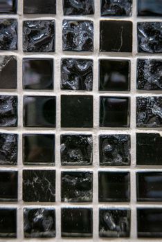 Black ceramic mosaic on the wall as background.