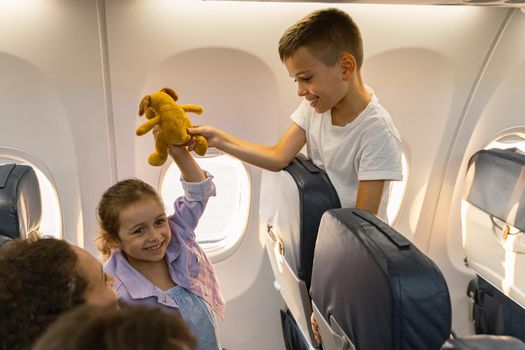 Happy little boy and girl having fun with toy while traveling with parents on a plane. Trip and family concept