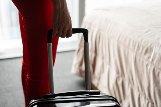 Young blond businesswoman arrives in a hotel room with black suitcase. Woman in red coral business suit.