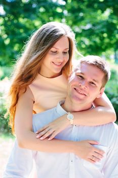 Young couple - girl huggs guy from a back and smiling