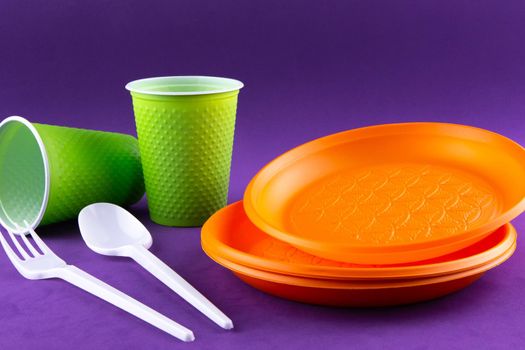 Plastic orange green waste collection on purple background. Concept of plastic pollution and ecology problem