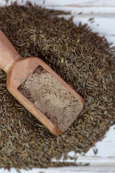 Grounded cumin seeds in a wooden spoon over the seeds