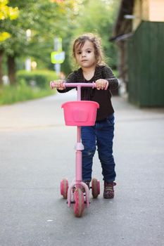 Yong kid girl ride on street on child scooter